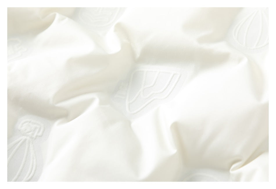 Close-up of white fabric with a repeating pattern of raised emblems and textured folds.