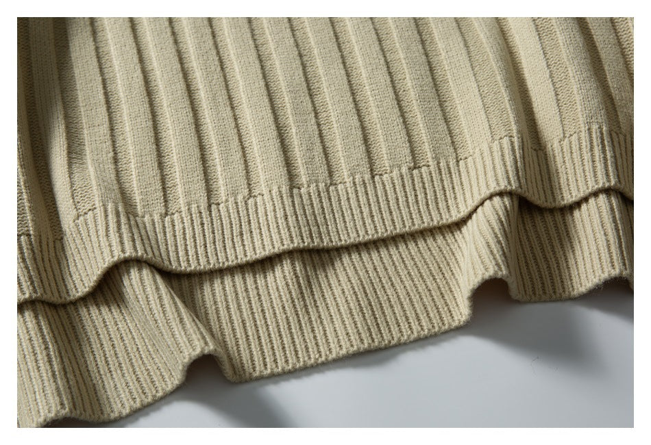 Close-up of the beige sweater's ribbed bottom hem and vertical knit texture.