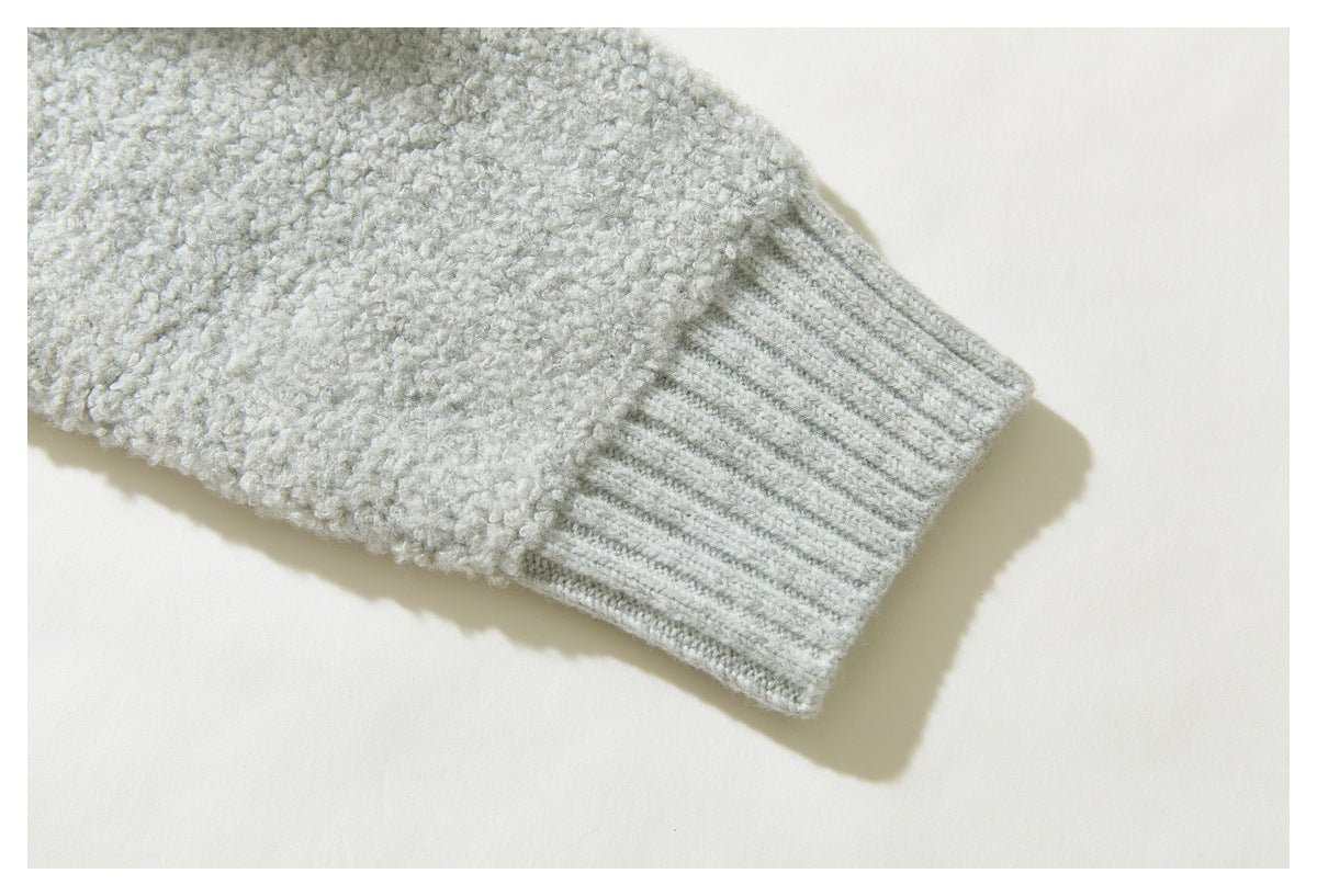 Close-up of a ribbed cuff on the sleeve of a light gray textured knit sweater.