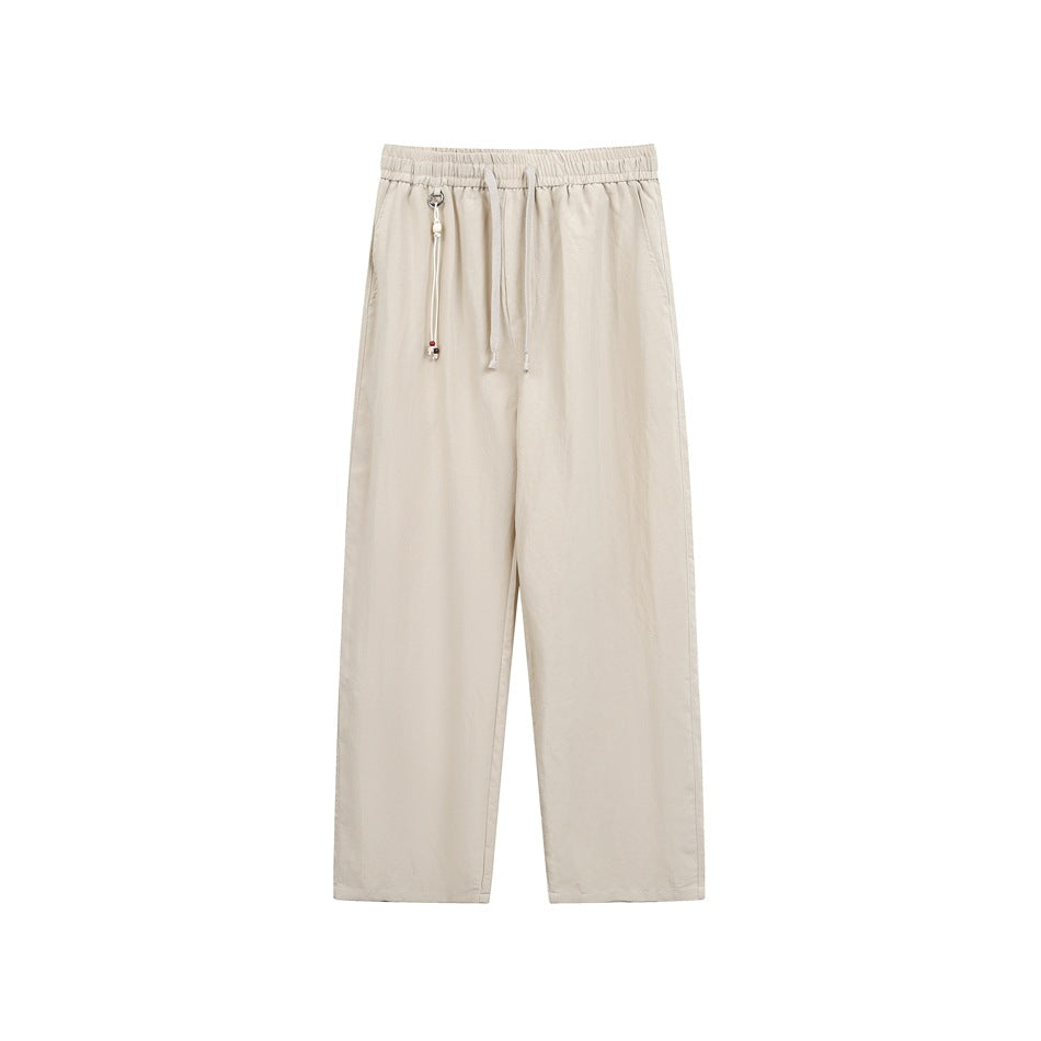 Light khaki beige straight-leg drawstring pants with elastic waist and beaded cord charm, front view