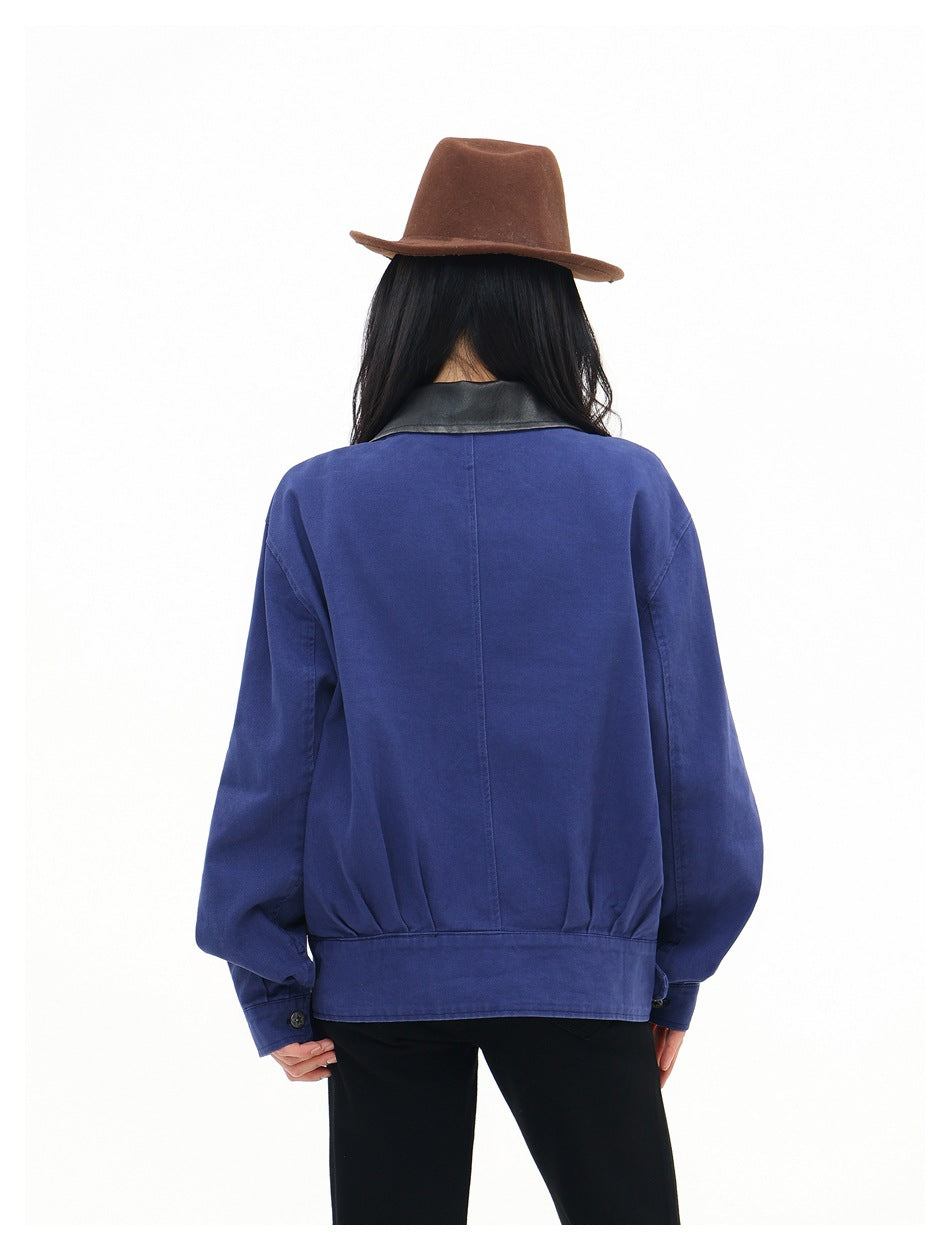 Back view of a woman wearing a blue jacket with black collar, center back seam and banded gathered hem