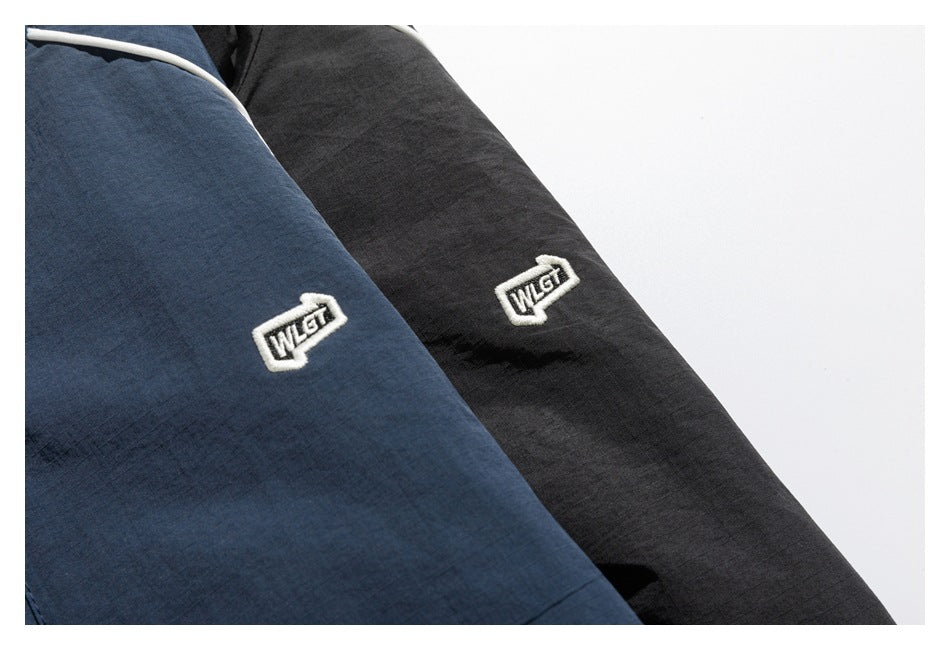 Close-up of navy and black garments, each with a small embroidered white badge.