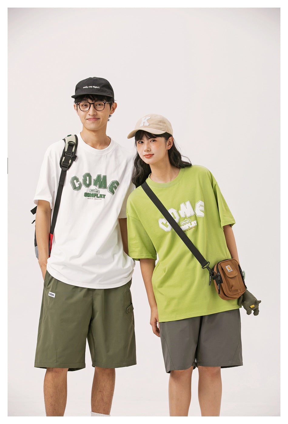 Two models wearing oversized graphic T-shirts: white with green print and lime green with white print.