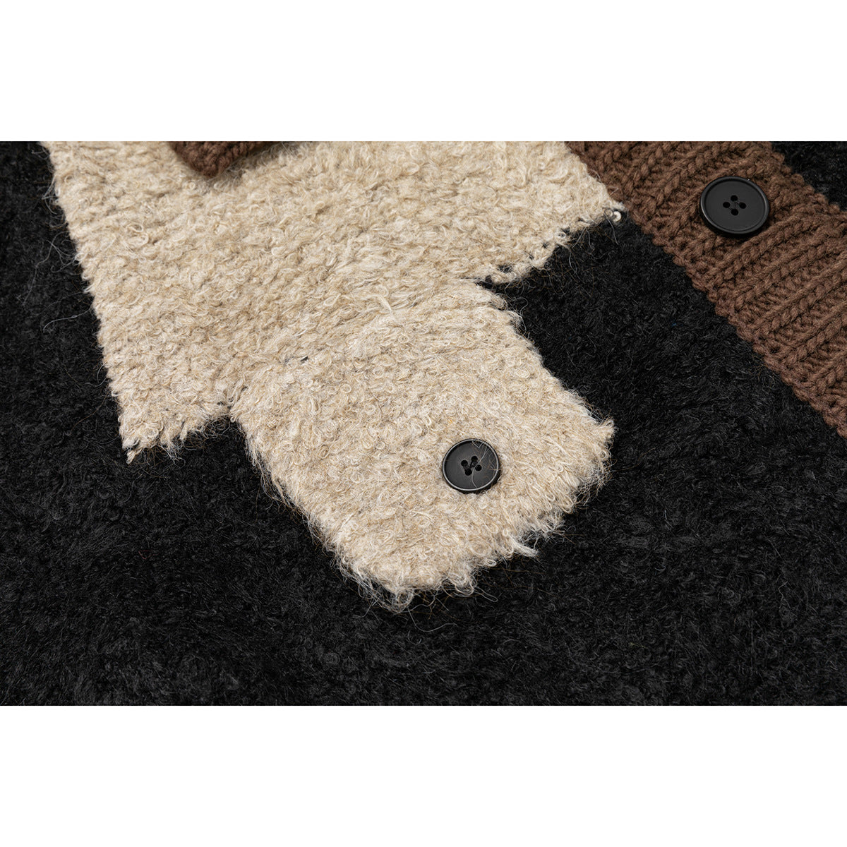 Close-up of the cardigan’s fuzzy cream and black knit panels with a black button on a brown ribbed section.