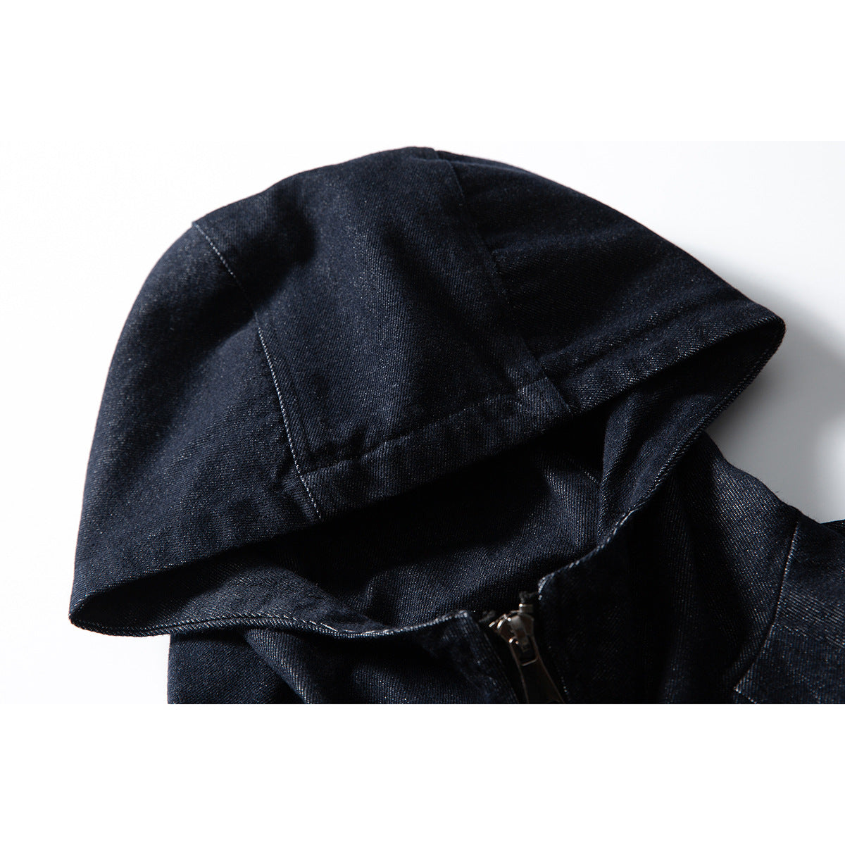 Close-up of a dark indigo hooded jacket showing the hood seams and front zipper.
