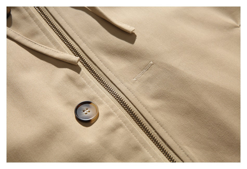 Close-up of a tan jacket front with a metal zipper, dark button, and stitched placket.