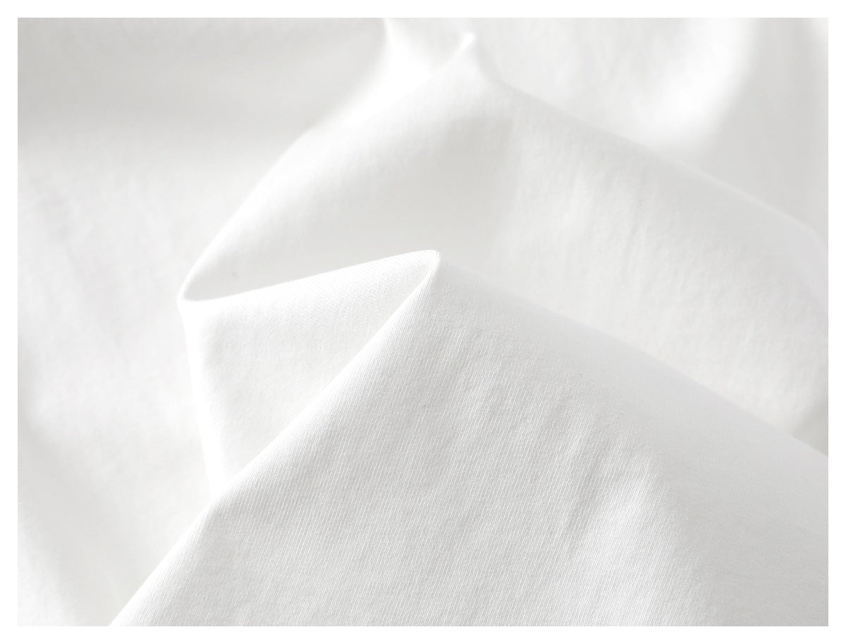 Macro view of the white shirt fabric draped in soft folds.