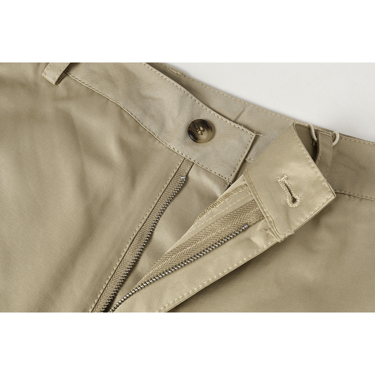 Close-up of beige trousers showing the waistband button, belt loop, and partially unzipped fly.