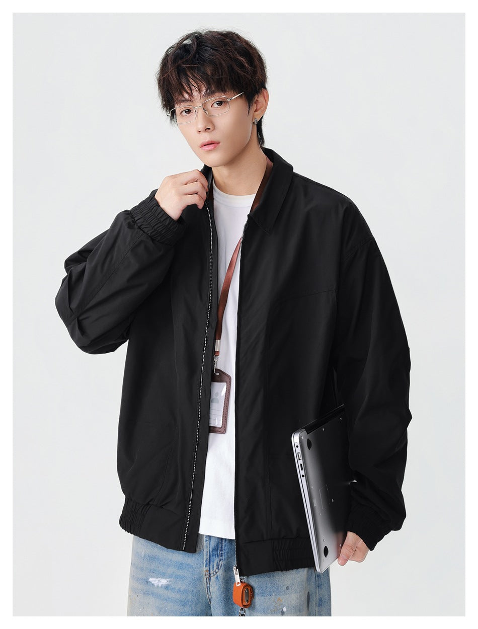 Model wearing a loose black zip-front jacket with a collar, elastic cuffs and hem, over a white shirt.