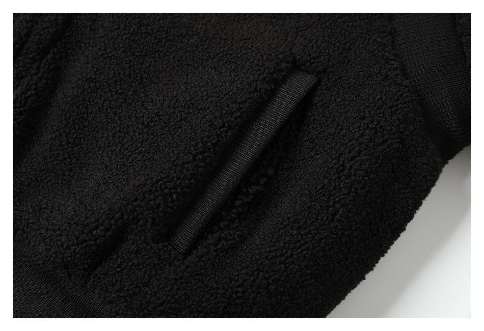 Close-up of a slanted pocket opening and ribbed trim on the black textured jacket.