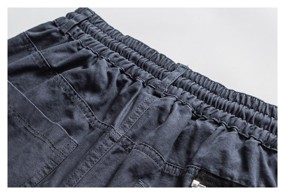 Close-up of dark charcoal shorts showing the gathered elastic waistband, belt loop, and pocket stitching.