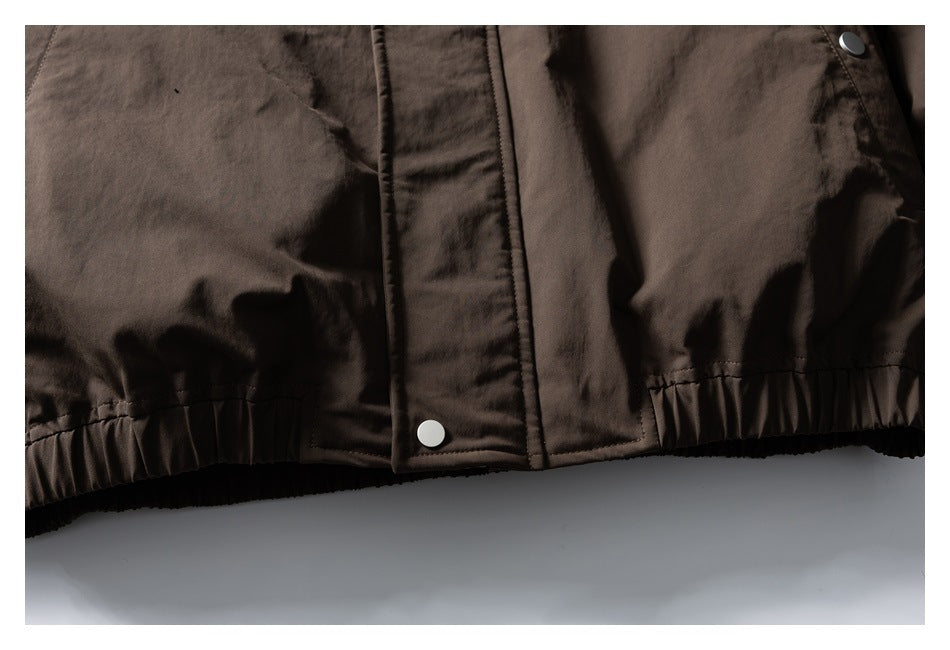 Close-up of the dark brown jacket's snap-button front placket and gathered hem.