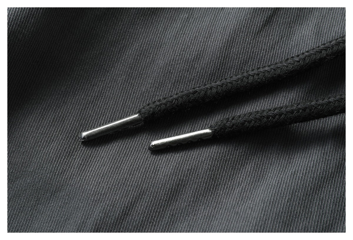 Close-up of the black drawstring tips against the ribbed charcoal fabric of the pants.