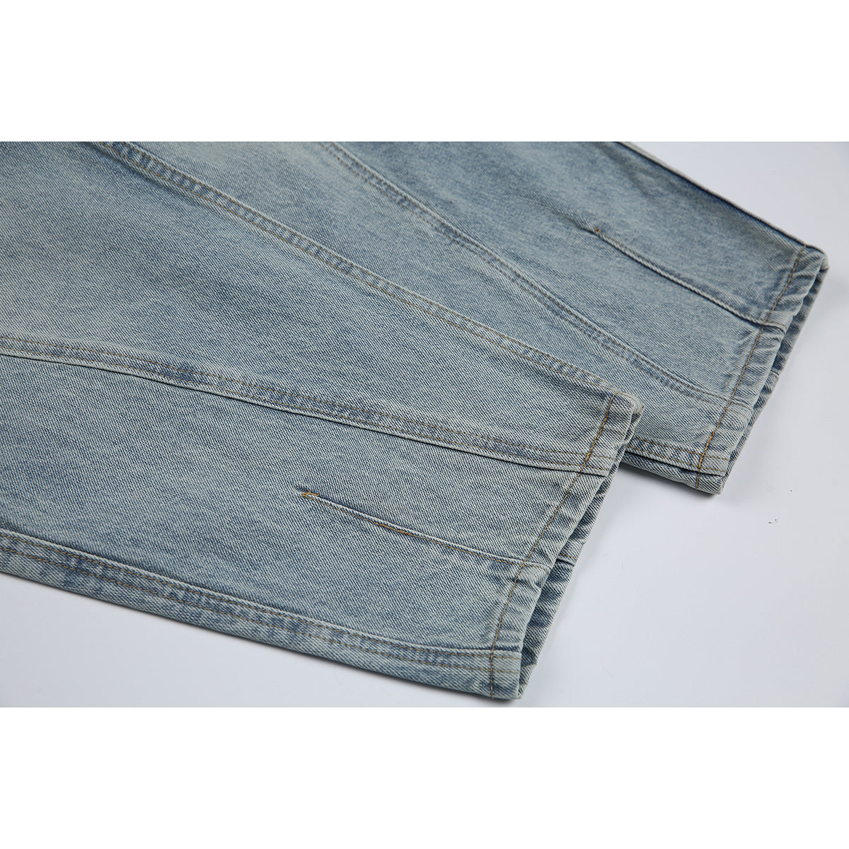 Close-up of the stitched hems on light blue washed denim jeans.