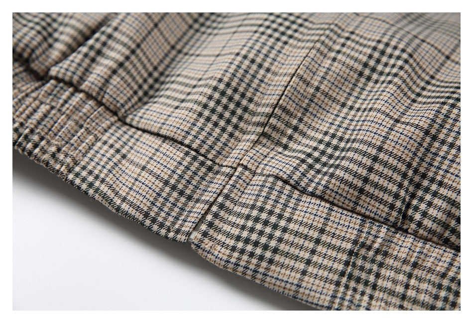 Close-up of a rectangular patch pocket on a beige, black, and blue plaid garment.
