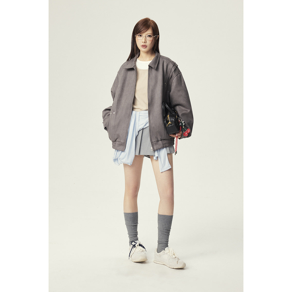 Model wearing an oversized gray zip-front jacket with a pointed collar and gathered hem.