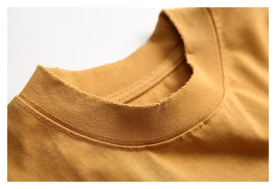 Close-up of a mustard-gold T-shirt's ribbed crew neckline and stitched collar seam.