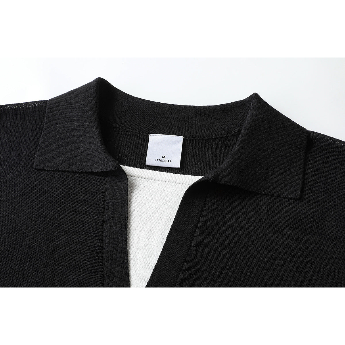 Close-up of a black short-sleeve collared knit shirt with a white inner layer and a visible M size tag.