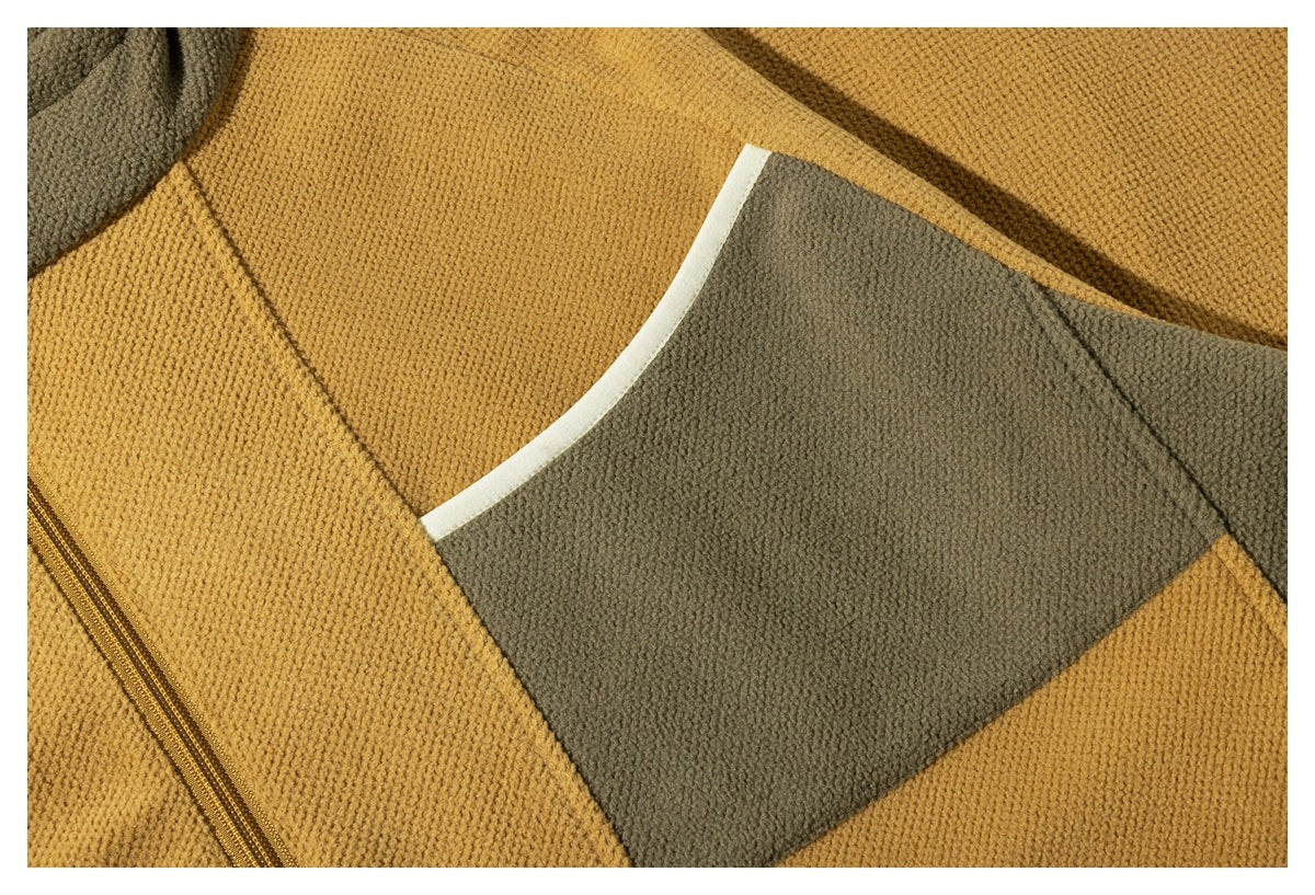 Close-up of a large olive chest pocket with light trim on a mustard jacket.