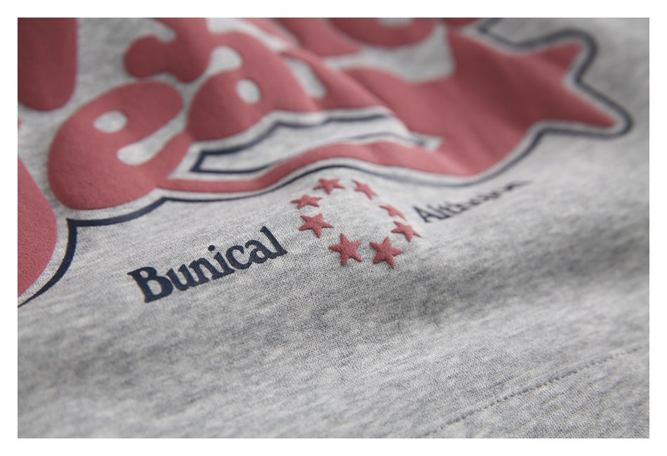 Close-up of the hoodie’s raised red chest graphic, navy outlines, stars, and small English lettering.