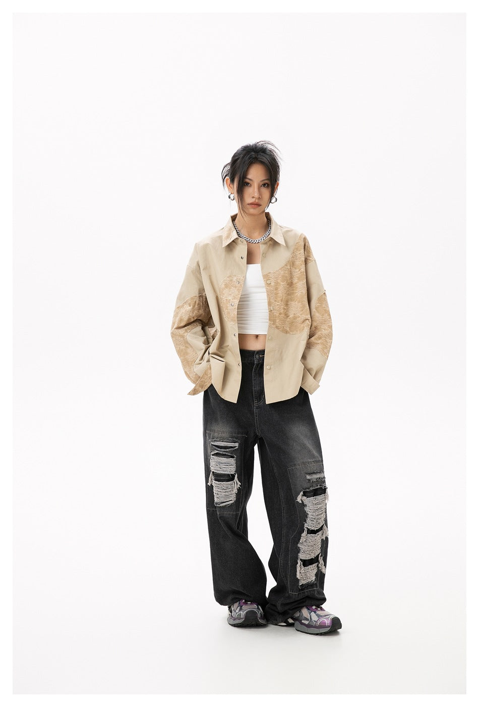 Model wearing the yellow patchwork shirt unbuttoned over a white top with ripped black jeans, slightly angled view