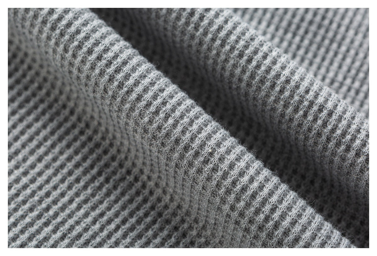 Macro view of folded gray waffle-knit fabric showing its raised texture.