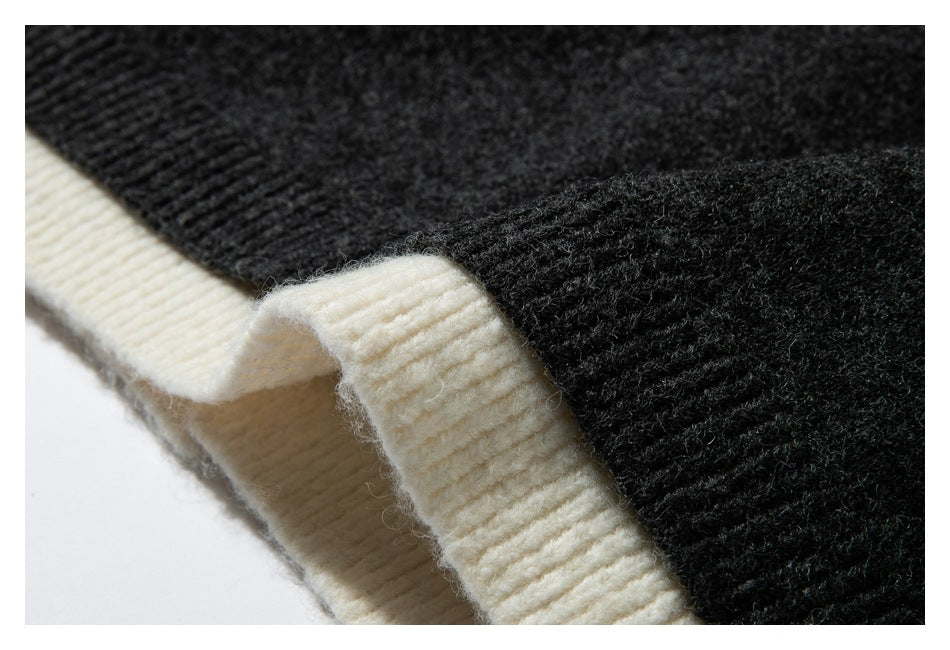 Close-up of the sweater's cream ribbed edge folded beside its dark charcoal knit body.