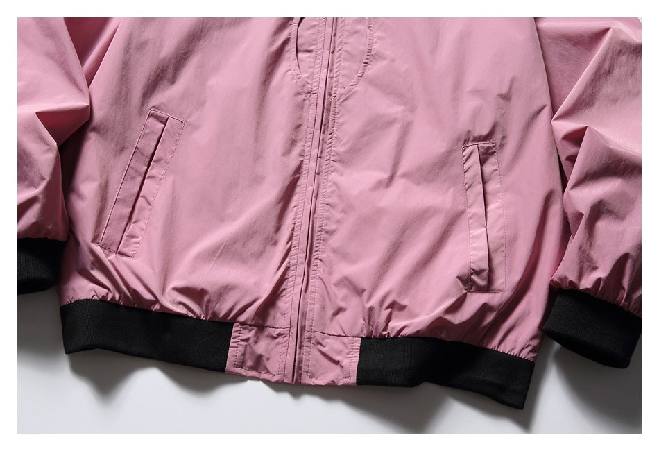 Close-up of a pink jacket front with zipper, slanted pockets, and black ribbed hem and cuffs.