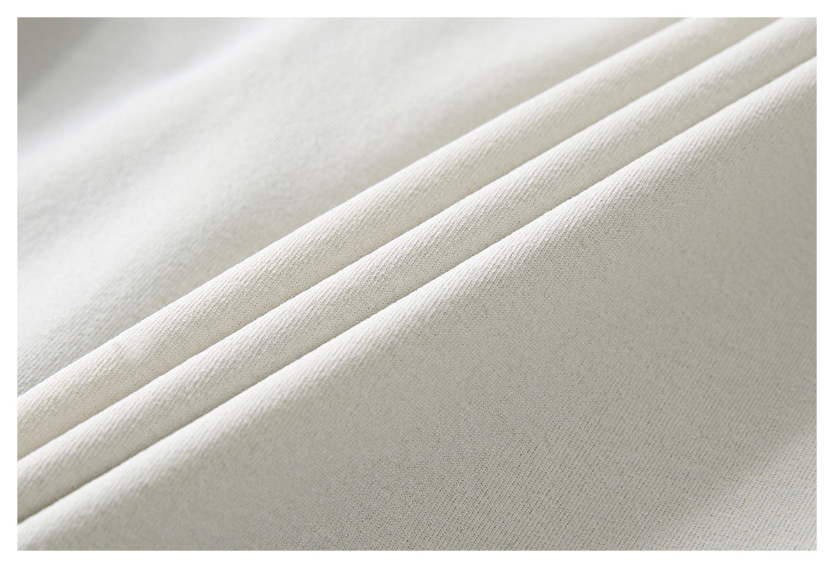 Extreme close-up of the ivory fabric's fine knit texture and soft folds.