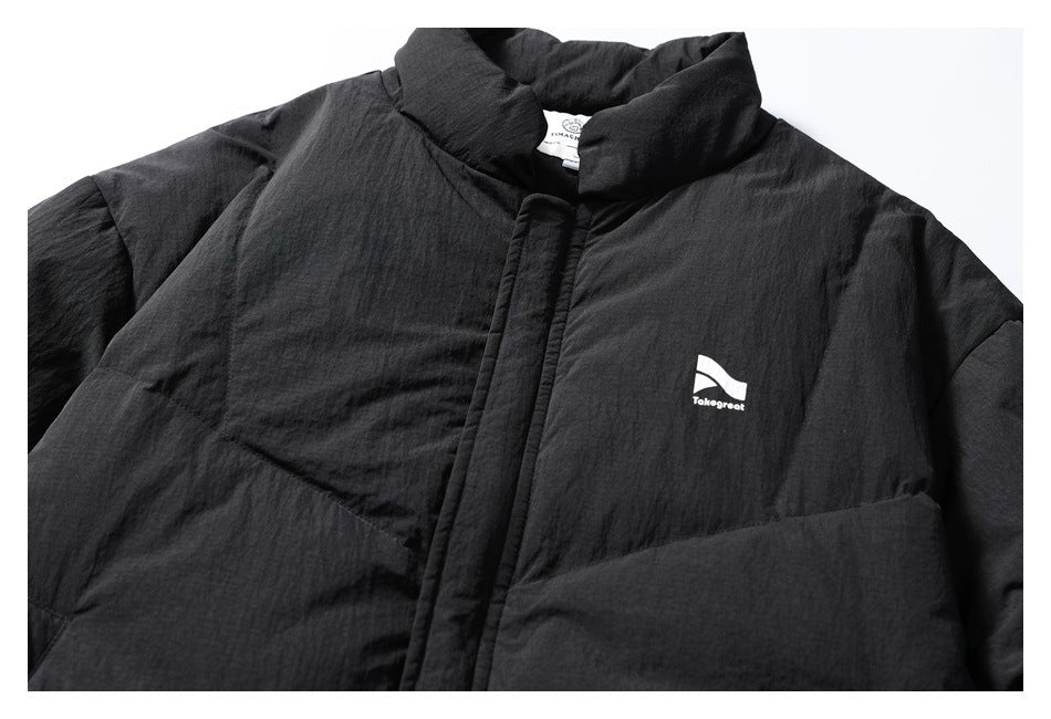 Close front view of a black padded jacket with a high collar, covered placket and small white Takegreat chest logo.