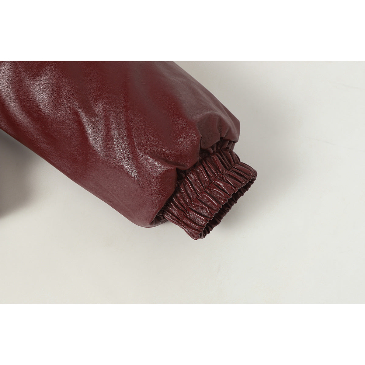 Close-up of a burgundy jacket sleeve ending in a gathered elastic cuff.