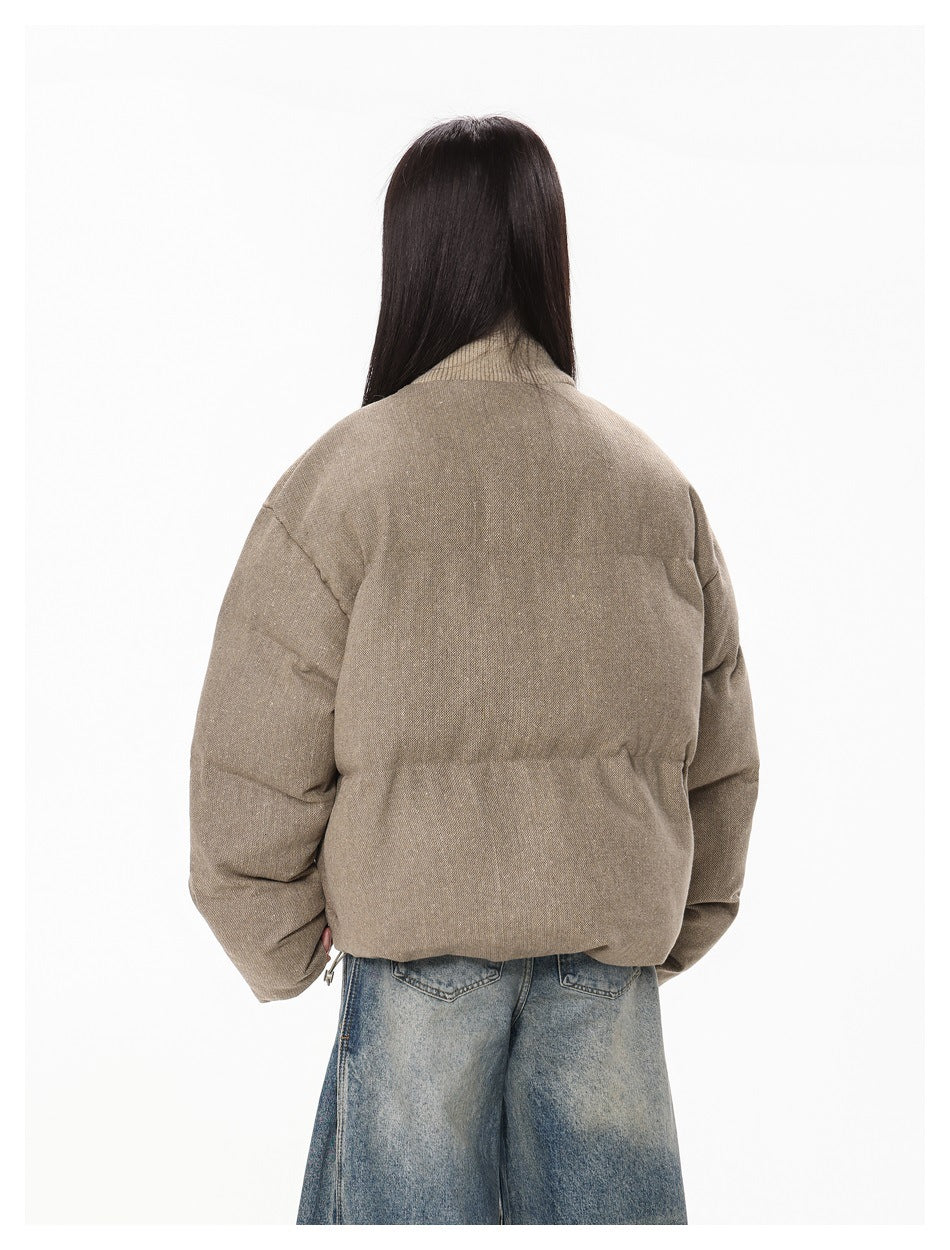 Rear view of a model wearing the taupe padded jacket, showing its plain back and gathered waist.