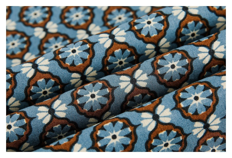 Macro view of blue floral fabric gathered into folds, showing its repeating flower pattern and texture.
