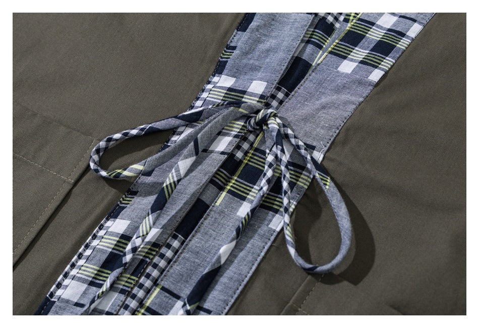 Close-up of the jacket's plaid front trim and tied waist cords against olive fabric.