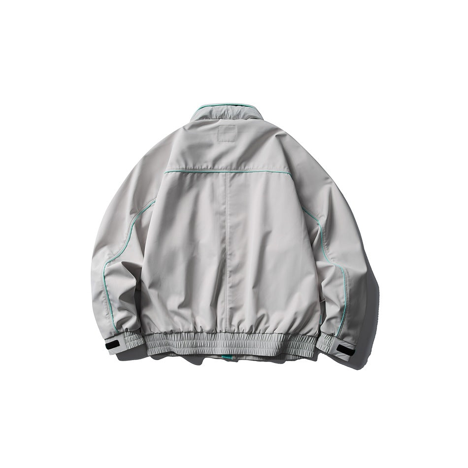 Back view of a gray jacket with teal piping, an elastic hem, and adjustable cuff tabs.