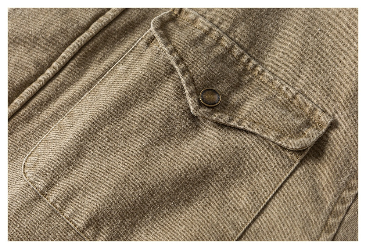 Close-up of a tan jacket's large flap pocket with a dark metal snap button.