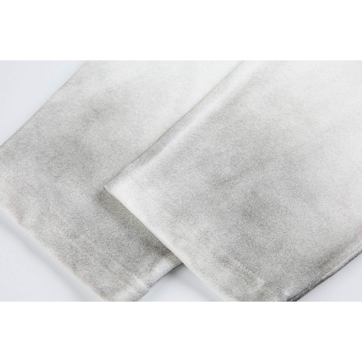 Close-up of overlapping light-colored shirt fabric and stitched hems.