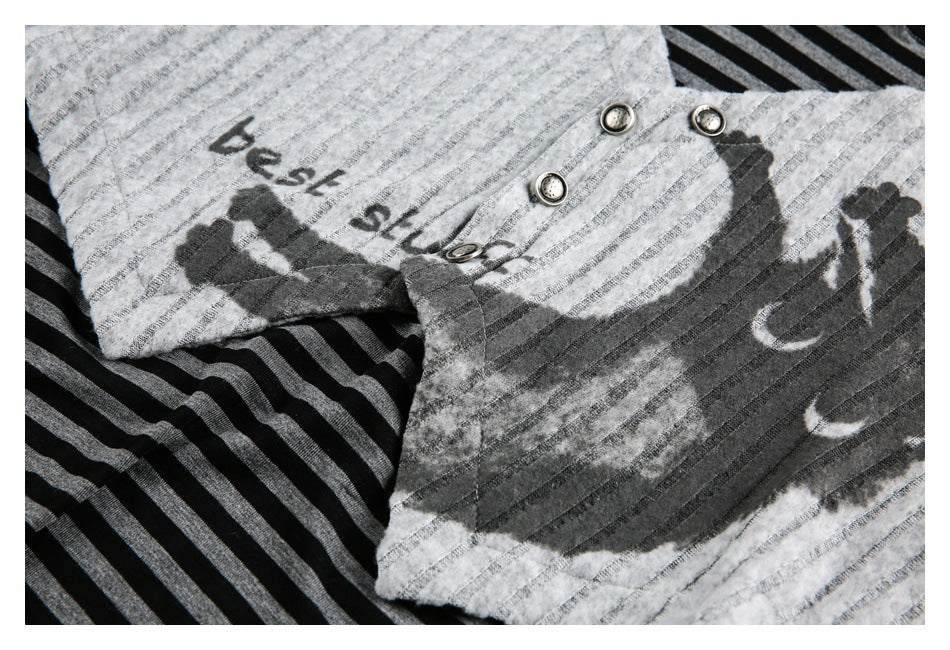 Close-up of a gray striped garment with metal buttons and dark graphic lettering and shapes.