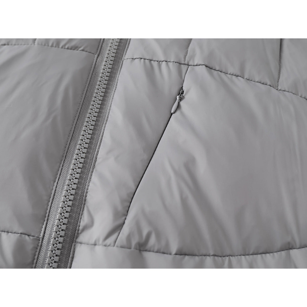 Close-up of the gray quilted jacket's front zipper and angled zip pocket.