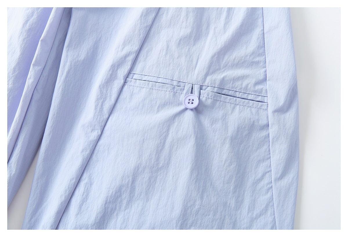 Close-up of pale lavender pants showing a buttoned welt pocket.