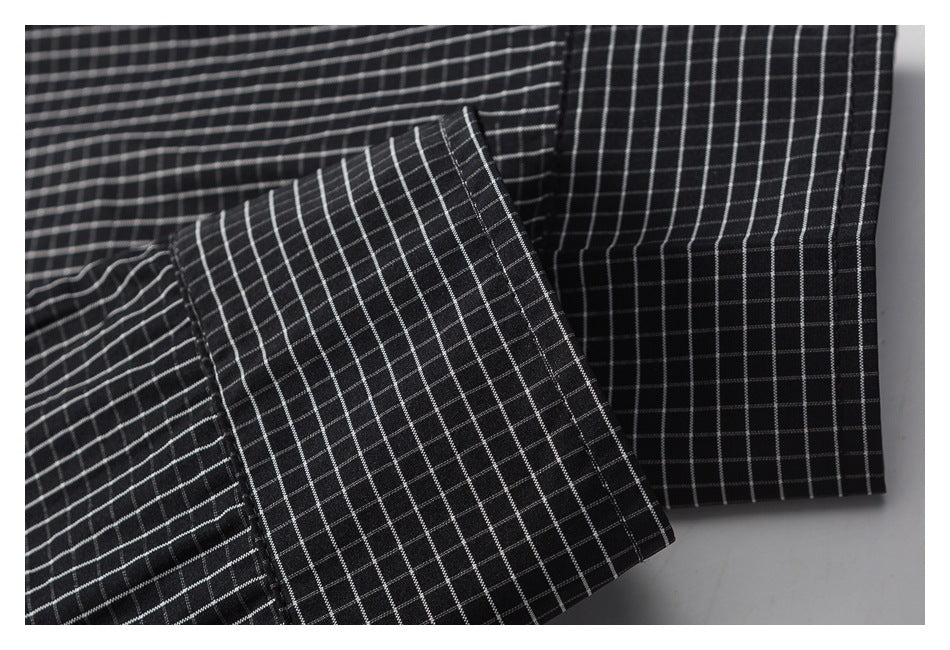 Close-up of a folded sleeve cuff on black fabric with a thin white grid pattern.