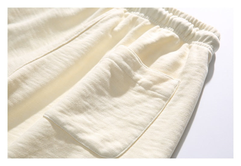 Close-up of a cream pants pocket and gathered elastic waistband.