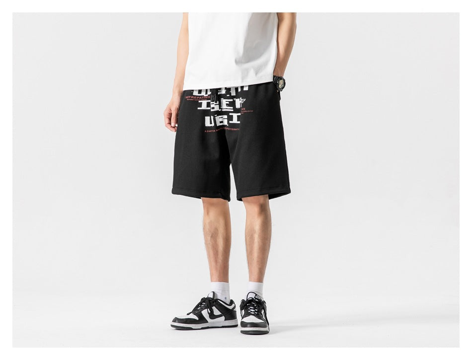 Front view of a model wearing black knee-length shorts with a large white and red graphic print.