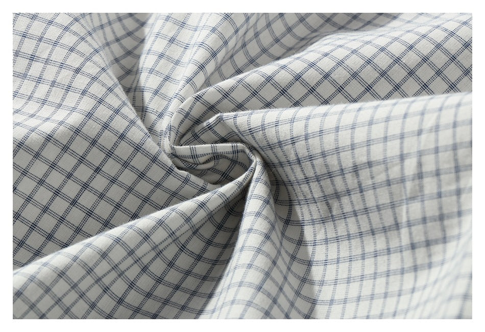 Close-up of white fabric with a blue-gray check pattern gathered into folds.