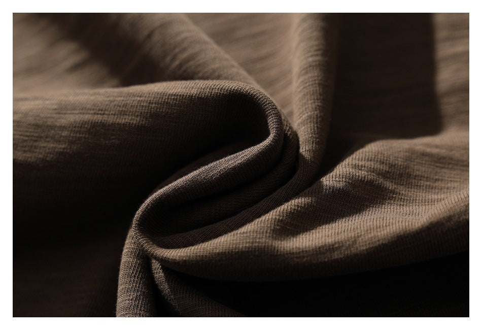 Brown knit fabric draped in soft folds, highlighting its fine surface texture.