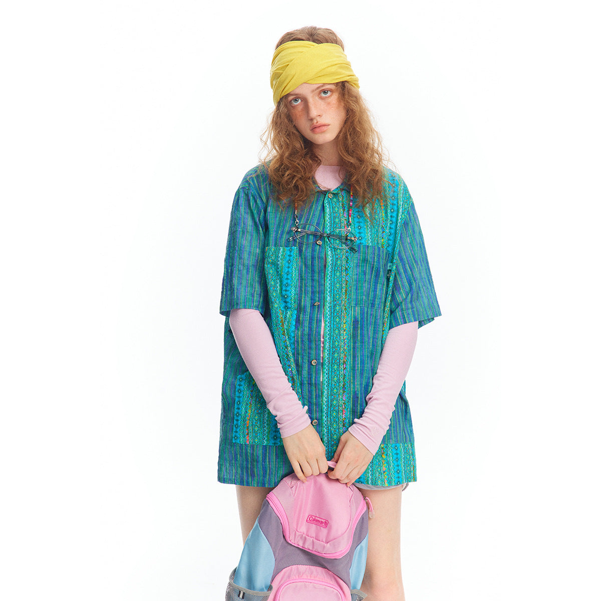 Front view of a model wearing a blue and turquoise patchwork-pattern button-front tunic with short sleeves.