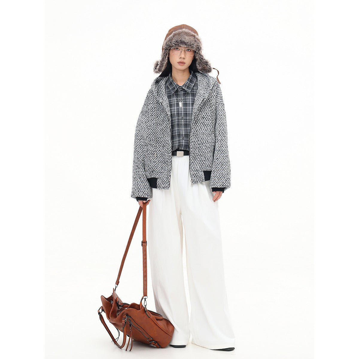 Model wearing an open black-and-white textured hooded jacket with dark cuffs, plaid shirt and wide white trousers.