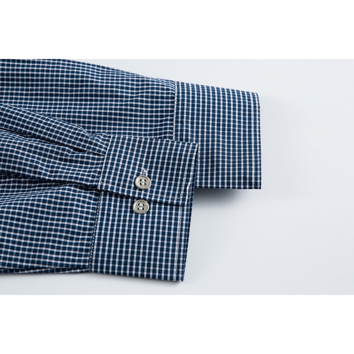 Close-up of a navy-and-white gingham shirt sleeve cuff with two buttons.
