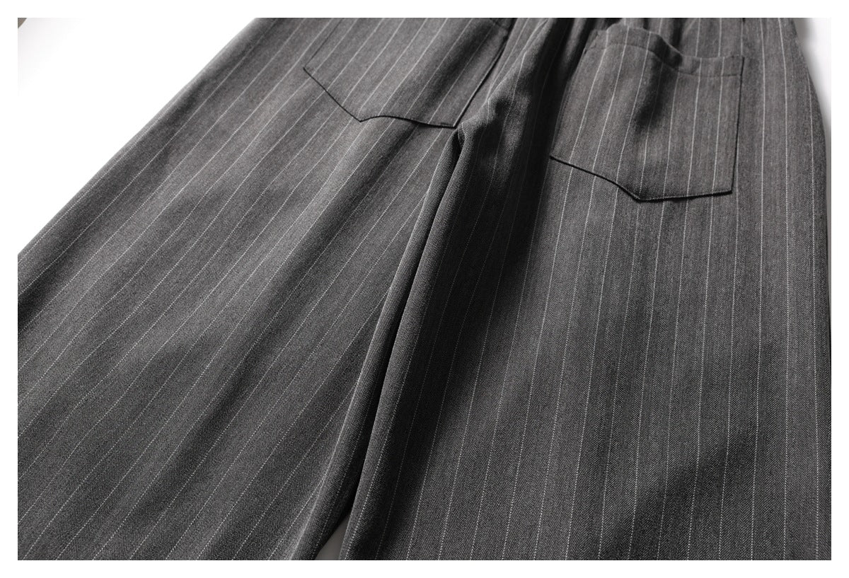 Close-up of charcoal pinstripe trousers showing two rear patch pockets and the upper legs.