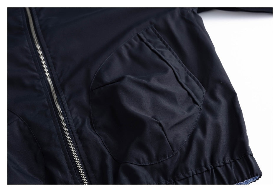 Close-up of a dark navy jacket showing a zip front, large angled pocket, and gathered hem.